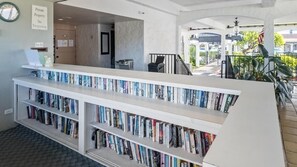 A reception area with a bookshelf filled with books, a private property sign, and a door leading to another room. - Big Island Casa De Emdeko B326 1 Bedroom Apts (Kailua-Kona)