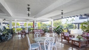 A covered outdoor area with tiled flooring, white furniture, and potted plants. - Big Island Casa De Emdeko B326 1 Bedroom Apts (Kailua-Kona)