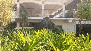A hotel with a central rock feature, balconies, and lush greenery. - Big Island Casa De Emdeko B326 1 Bedroom Apts (Kailua-Kona)