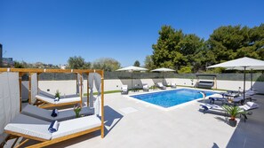 Ein Poolbereich mit Liegestühlen, einer Holzpergola und einem Schwimmbecken.