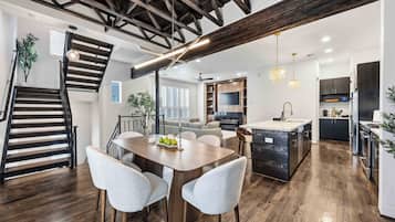 Uma cozinha moderna com ilha central, soalho de madeira e escada com vigas à vista.