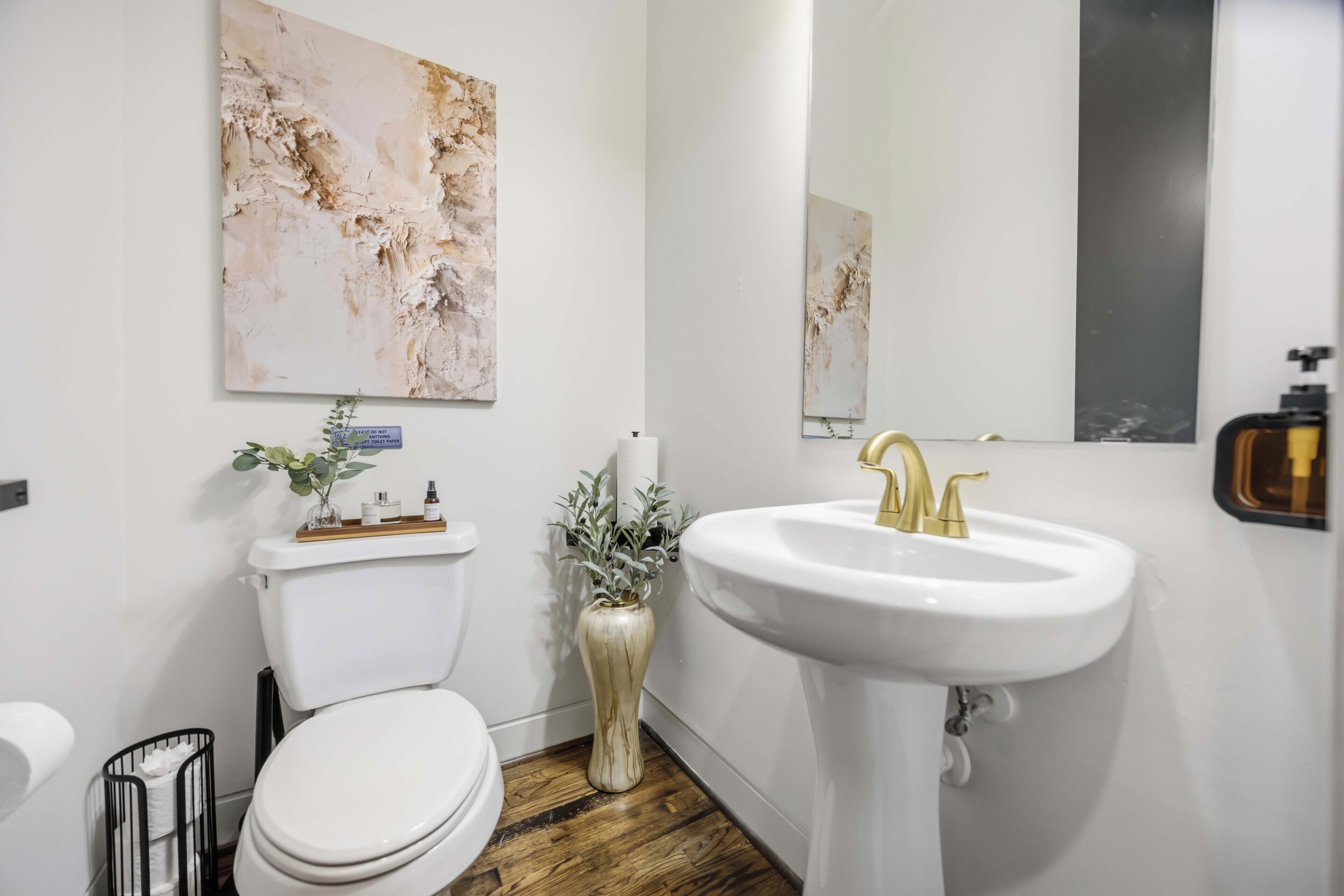 Un baño moderno con inodoro, lavamanos y un espejo grande.