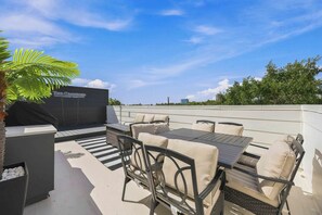An outdoor patio area with a table and chairs, a grill, and a sign that reads 'The Crawford Houston Texas.' - The Crawford HTX: Houston luxury with style, rooftop views, & local flair. (Houston)