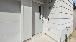Ein Wohngebäude mit einer Garagentür, einer Tür mit Fenster und der Hausnummer 4710 an der Seite.