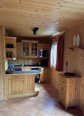 Cucina in legno con isola centrale, pensili, un forno a microonde e un lavello.