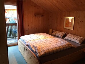 A wooden cabin bedroom with a single bed, a window with curtains, and a framed picture on the wall. - Chalet # 49 with 3 BR for up to 8 people (Annaberg)