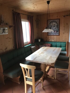 A wooden interior with a green upholstered bench, a wooden table, and a hanging light fixture. - Chalet # 49 with 3 BR for up to 8 people (Annaberg)