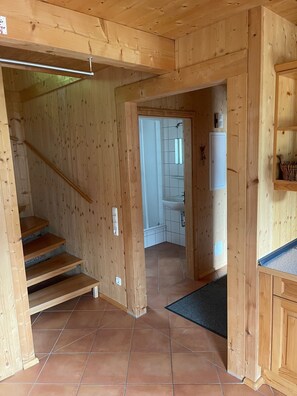 A wooden interior with a staircase, a kitchen area, and a bathroom visible through an open doorway. - Chalet # 49 with 3 BR for up to 8 people (Annaberg)