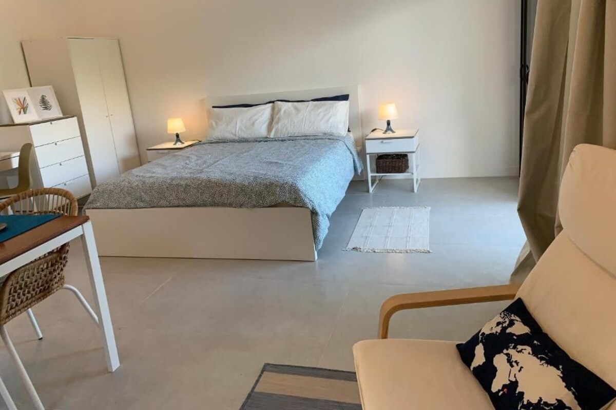 A bedroom with a bed, bedside tables, a chair, and a desk.
