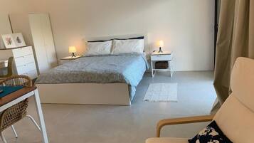 Ein Schlafzimmer mit einem Bett, Nachttischen, einem Sessel und einem Schreibtisch.