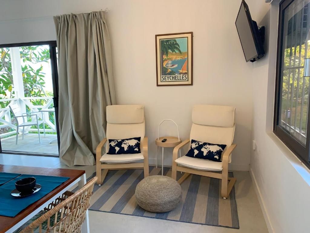 A room with two chairs, a small table, a globe, and a framed picture of Seychelles.