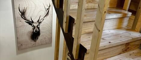 Un escalier en bois, avec une tête de lit en bois et une ramure de cerf fixée au mur.