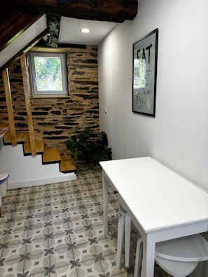 A room with a staircase, a white table, and a wall with a framed poster.