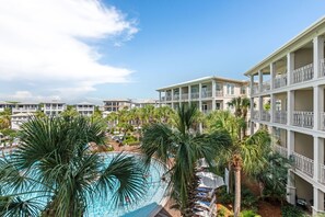 Um resort com piscina rodeada por palmeiras e edifícios altos com varandas.