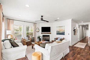 A living room with a fireplace, white sofas, a coffee table, and a ceiling fan. - 4BR in Seacrest Beach w 4 Bikes & Lagoon Pool Views + Attraction Tickets! (Seacrest)