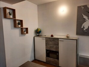 Una cocina compacta con electrodomésticos integrados, estanterías de madera con plantas en macetas y un globo en la encimera.