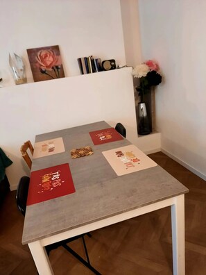 Una mesa de comedor con individuales, un jarrón con flores y un cuadro en la pared.