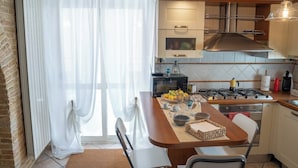 A modern kitchen with a gas stove, a microwave, and a kettle on the countertop.