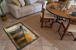 A dining area with a round table, chairs, and a glass-top table.