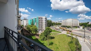 A cityscape with modern buildings, a green park, and a busy road with buses. - Apartamenty Sun & Snow Belwederska (Warszawa)
