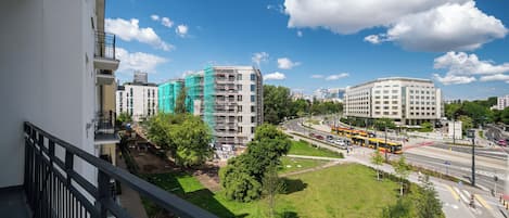 A cityscape with modern buildings, a green park, and a busy road with buses.