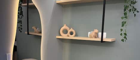 Un interior moderno con un sofá, dos cojines, un espejo y estantes con adornos.