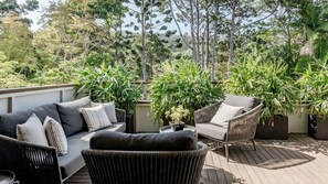 An outdoor patio area with a sofa, chairs, and potted plants. - Little Cove Luxury Escape (Noosa Heads)