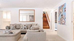 A modern living room with a sofa set, a coffee table, and a large mirror. - Little Cove Luxury Escape (Noosa Heads)