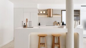A modern kitchen with a central island, bar stools, and a hanging light fixture. - Bella Vista Waterfront Luxury (Noosaville)