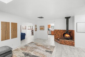 Una sala de estar moderna con chimenea, un sofá azul y obras de arte en las paredes.