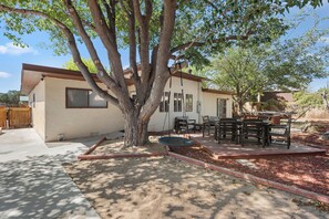 A residential property with a patio area, outdoor furniture, and a large tree.