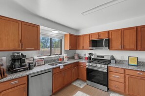 Una cocina moderna con gabinetes de madera, electrodomésticos de acero inoxidable y encimeras de granito.
