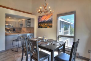A modern kitchen with stainless steel appliances, a dining area with a table set for four, and a large window offering a view of the outdoors. - Updated Animas Valley Condo with Awesome Views - 2 Decks (Durango)