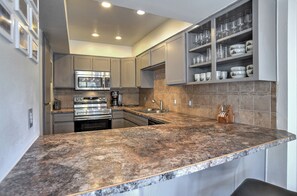 Uma cozinha moderna com bancadas de granito, eletrodomésticos de aço inoxidável e uma adega embutida.