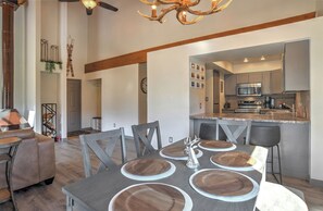 A modern kitchen with stainless steel appliances, a dining area with a wooden table and chairs, and a visible living area with a sofa and a fireplace. - Updated Animas Valley Condo with Awesome Views - 2 Decks (Durango)