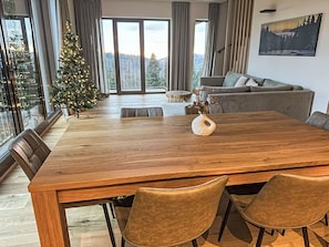 Ein moderner Essbereich mit Holztisch, Ledersesseln, einem Weihnachtsbaum und Blick ins Freie.