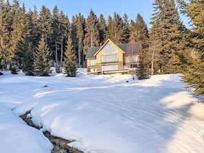 Eine Hütte, umgeben von schneebedecktem Boden und immergrünen Bäumen.