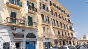 Un edificio de varios pisos con balcones, una puerta azul y un letrero que dice 'Officina Adamo'.