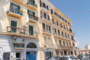 Un edificio de varios pisos con balcones, una puerta azul y un letrero que dice 'Officina Adamo'.