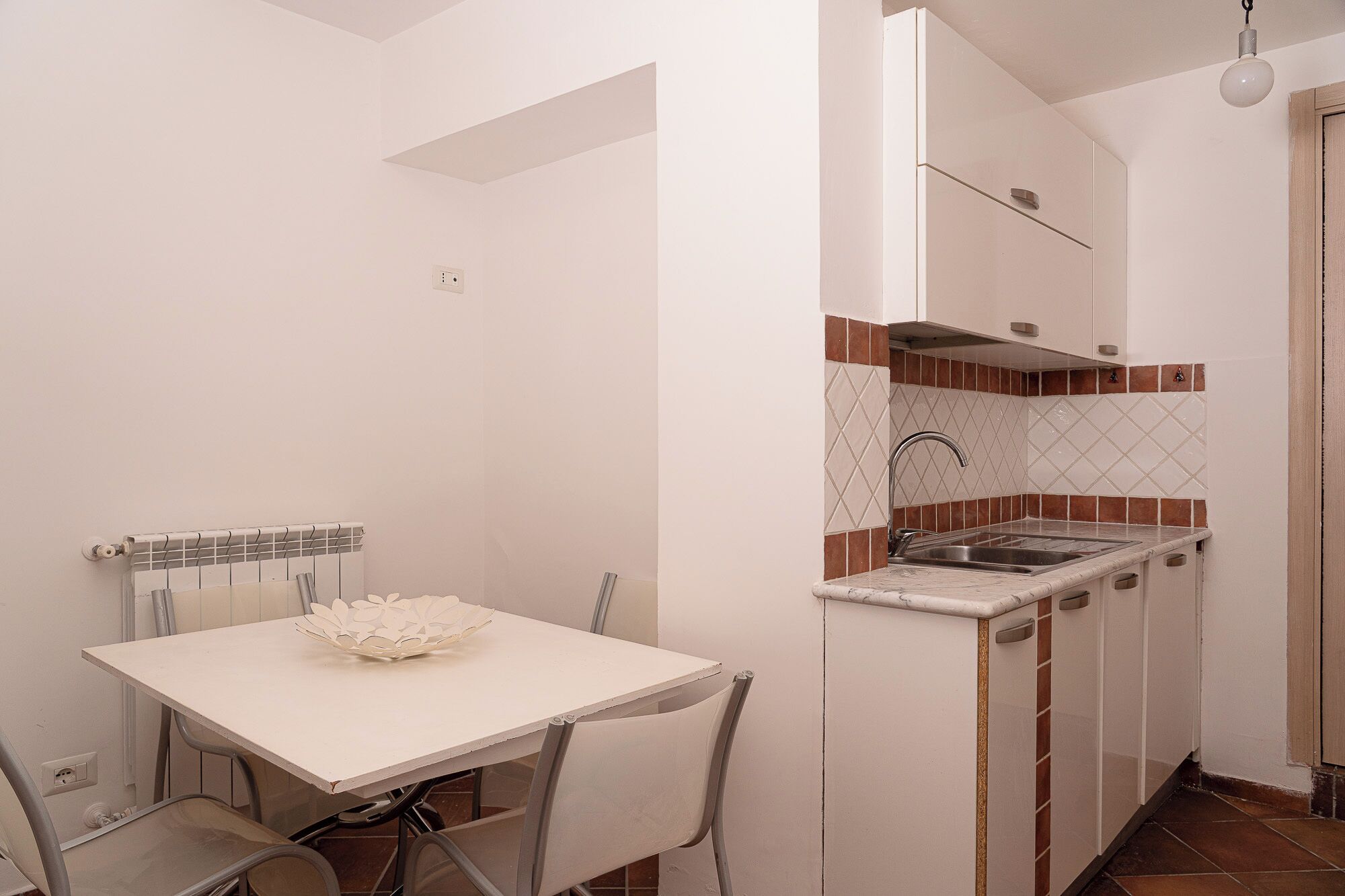A compact kitchen with a white countertop, a sink, and a backsplash with a diamond pattern.