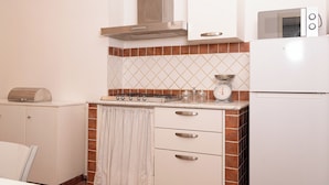 Una cocina compacta con estufa, microondas y refrigerador pequeño.