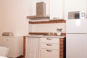 Una cocina compacta con estufa, microondas y refrigerador pequeño.