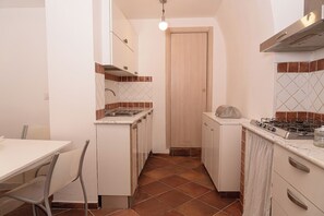 Cuina compacta amb fogó de gas, un rentatallops i una petita encimera.