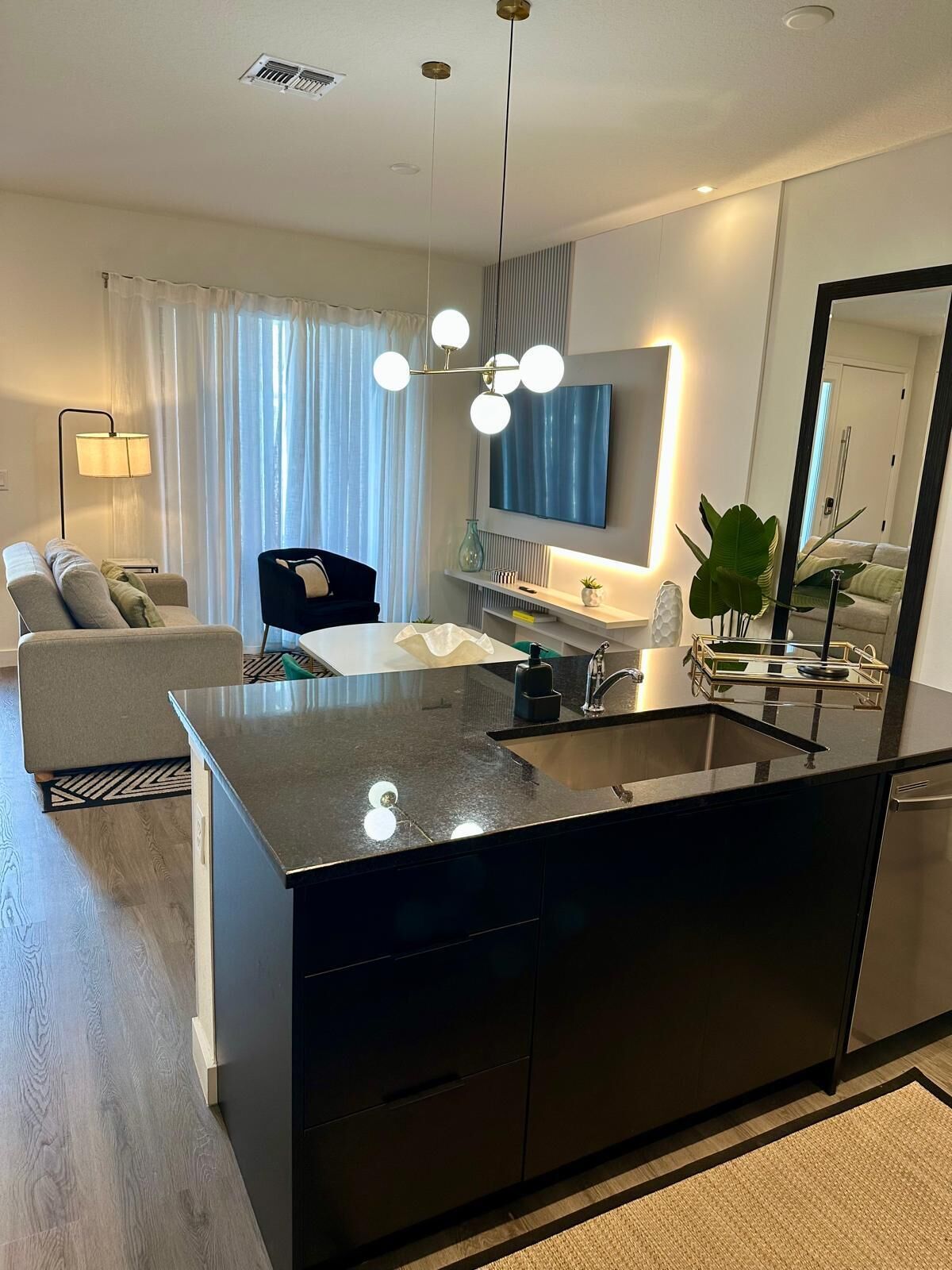 Una cocina moderna con una isla central, un área de comedor con un sofá y una sala de estar con televisor.