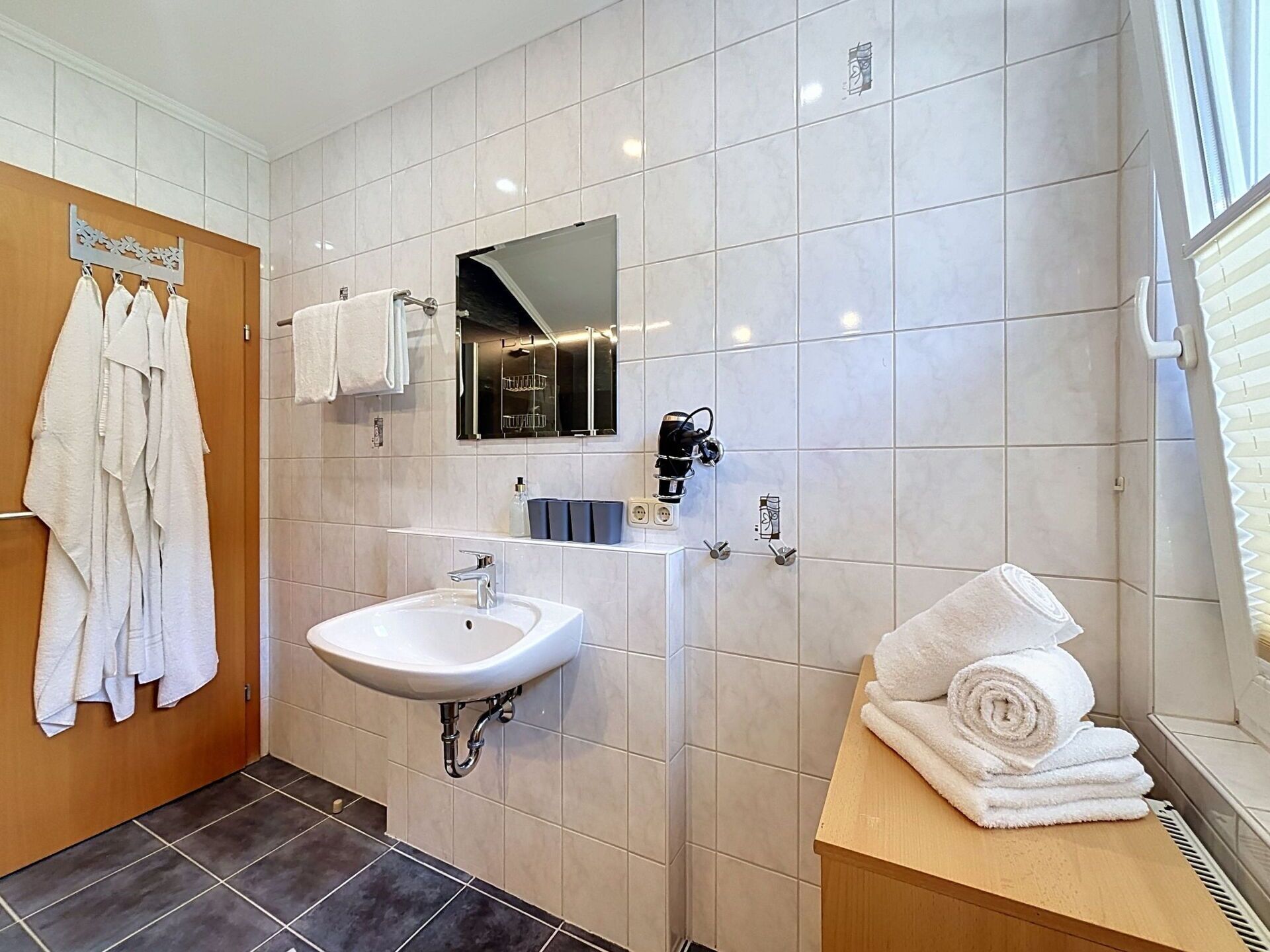 A modern bathroom with a white sink, a mirror, and a towel rack.