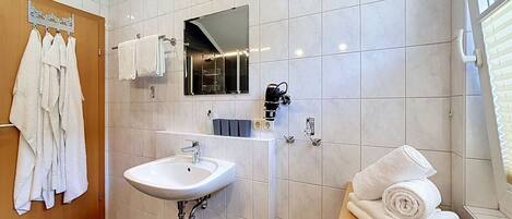 A modern bathroom with a white sink, a mirror, and a towel rack.