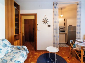 Ein kompakter Wohnbereich mit einer Küchenzeile, einem Essbereich und einer gemütlichen Sitzecke mit einem gemusterten Sofa.