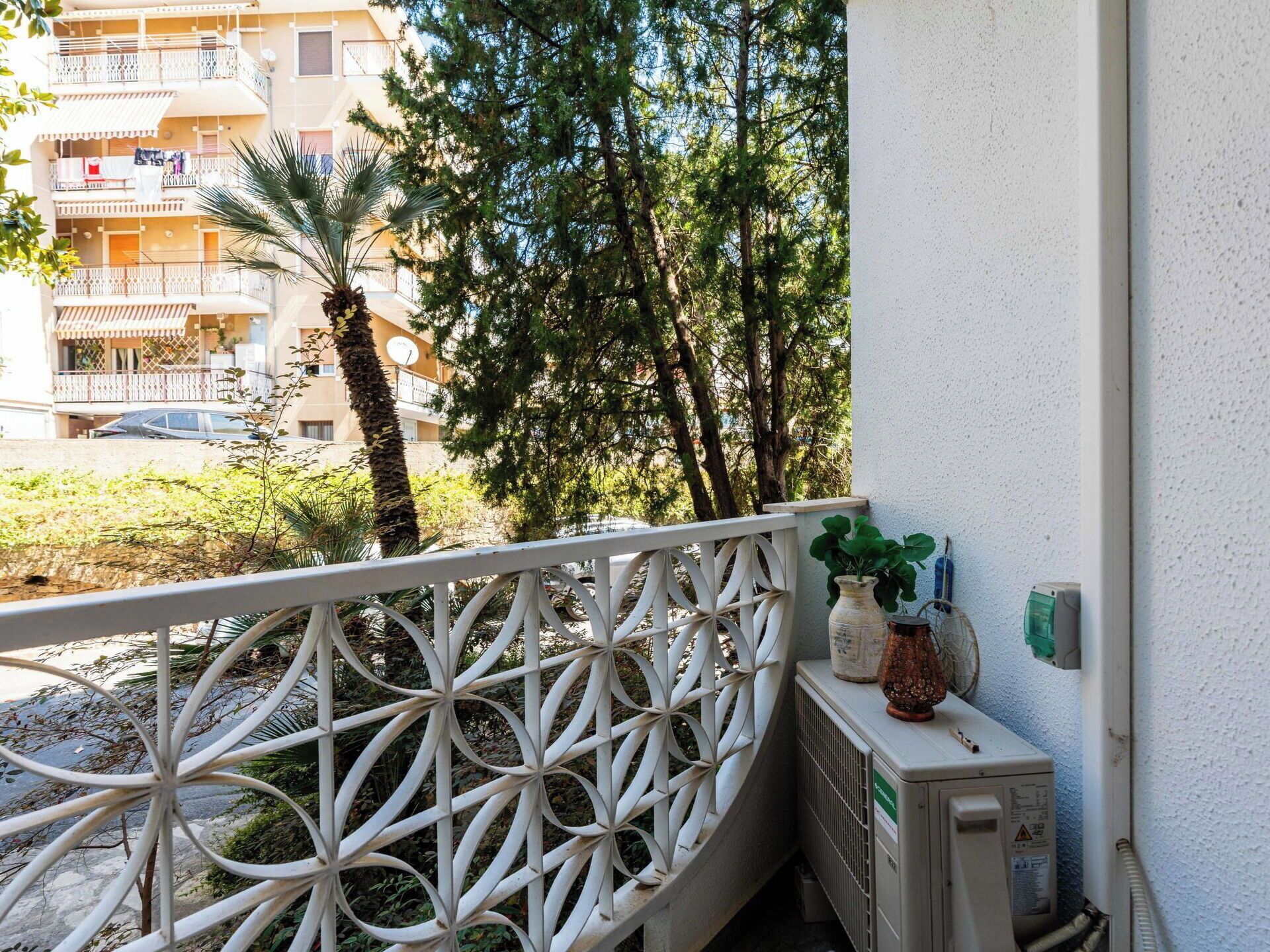 A balcony with a white railing, a radiator, and a potted plant.