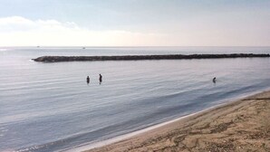 A beach with calm water, a rocky breakwater, and a sandy shore. - Cosy apartment for 3 guests with WIFI, A/C, TV, balcony and pets allowed (Santo Stefano Al Mare)