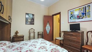 Ein Schlafzimmer mit einem Bett, einem Schminktisch, einem Stuhl und einem Bild an der Wand.